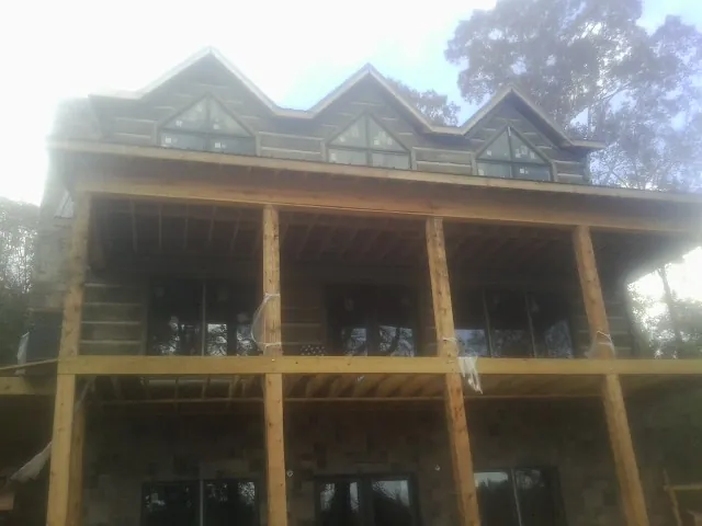 Dormers and porch framing on a large log home under construction — Roof Coating work by our crew in Dobson