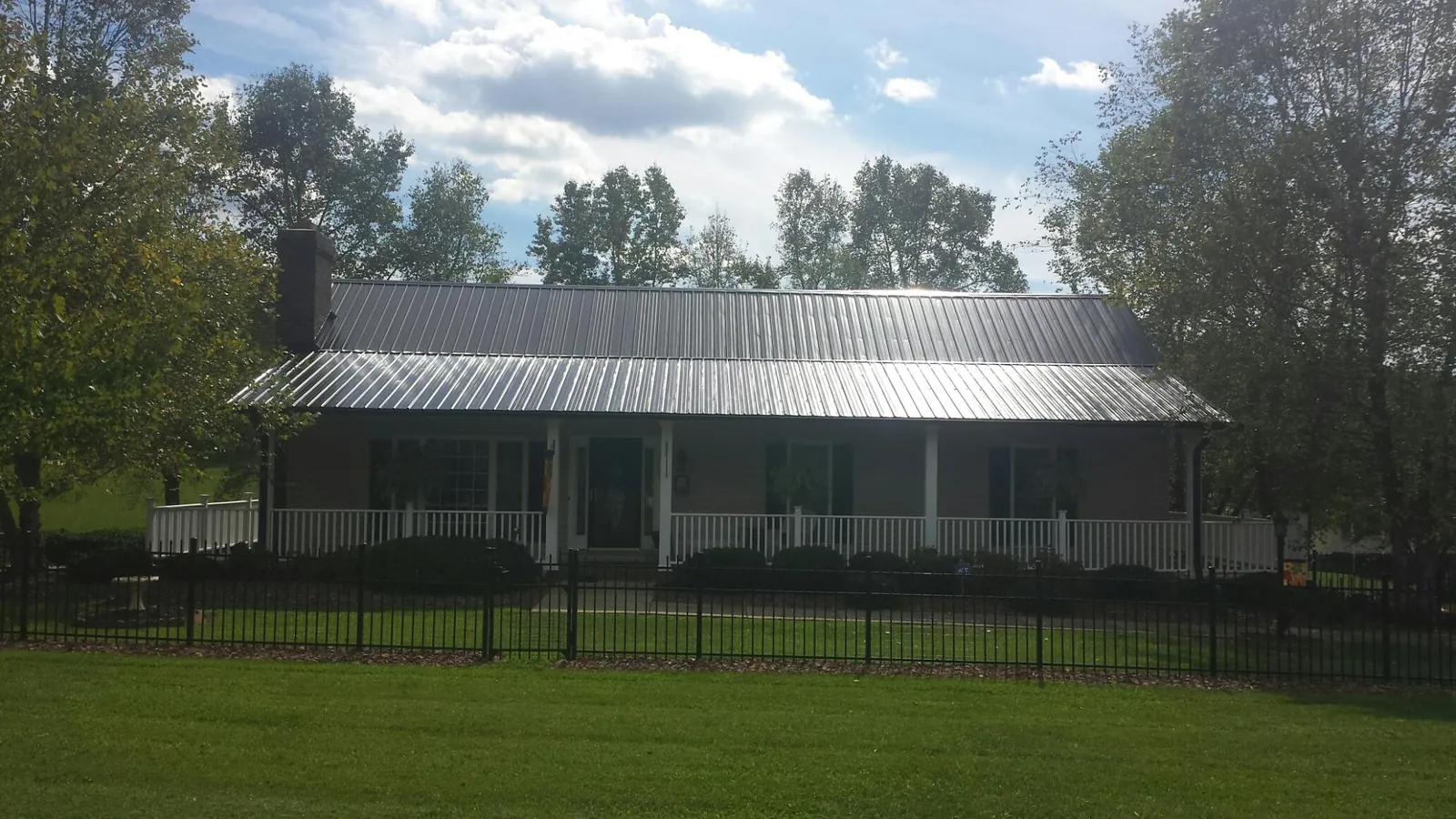 Gray metal roof on a brick ranch with a full width front porch — Gutter Guard Installation work by our crew in Dobson